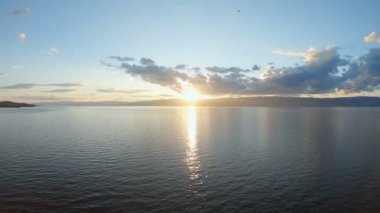 Güzel deniz manzarası. Gün batımında göl kıyısı. Çarpıcı manzara, mavi su ve gökyüzü, parlak güneş ve altın kıyı. Manzara. Havadan çekilmiş, 4k