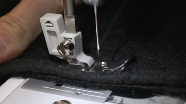 Primer plano de la aguja de la máquina de coser se mueve hacia arriba y hacia abajo. Tejido negro — Vídeo de stock