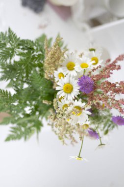 Papatya ve beyaz bir masaya diğer çiçek.