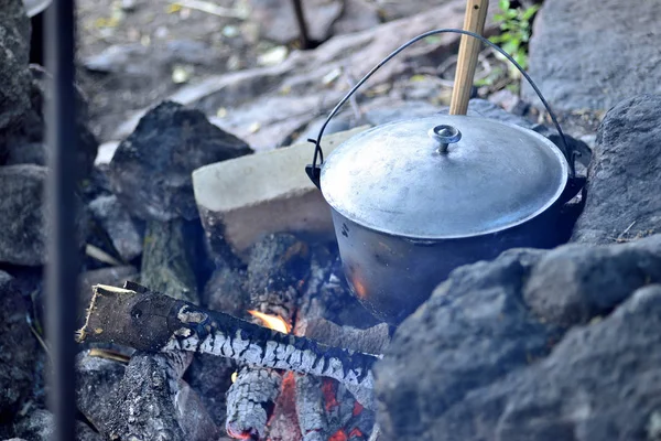 Cooking in a cauldron on an open fire. Preparing food at the stake in a wild camping. to cook dinner in a pot on fire. to eat outdoors in the camping — Stock Photo, Image