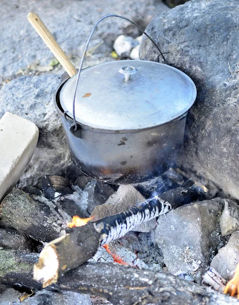 Cooking in a cauldron on an open fire. Preparing food at the stake in a wild camping. to cook dinner in a pot on fire. to eat outdoors in the camping — Stock Photo, Image