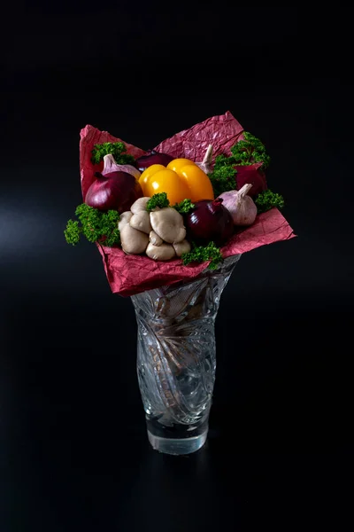 Unique festive bouquet of yellow peppers, red onions, garlic, mushrooms and parsley on a black background. Vegetable bouquet.