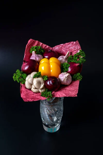 Unique festive bouquet of yellow peppers, red onions, garlic, mushrooms and parsley on a black background. Vegetable bouquet.