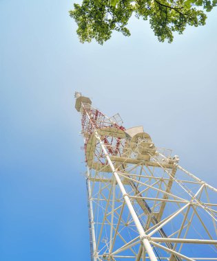 Gökyüzü altında bir sürü farklı antenle kırmızı ve beyaz iletişim kulesi.