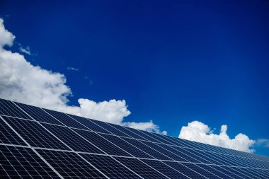 Güneş panelleri. Elektrik santrali. Mavi güneş panelleri. Alternatif elektrik kaynağı. Güneş çiftliği. Ekolojik yenilenebilir enerji kaynağı. Güneş enerjisi, fotovoltaik enerji santrali ve bulutlu mavi gökyüzü