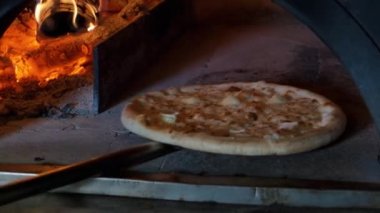 Fırında 4 peynirli İtalyan pizzası pişiriliyor, restoran şefi restoranda ahşap fırında pizza yiyor..