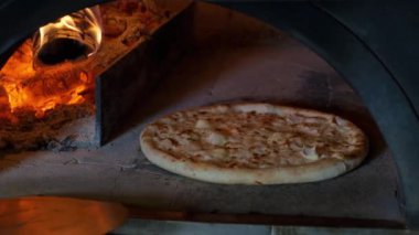 Fırında 4 peynirli İtalyan pizzası pişiriliyor, restoran şefi restoranda ahşap fırından pizza çıkarıyor..