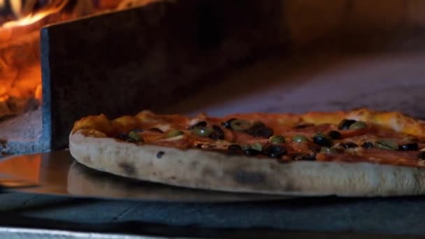 La pizza italiana con tomates se cocina en el horno, el chef del restaurante saca la pizza del horno de leña en el restaurante . — Vídeo de stock