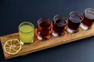Soğuk votka kokteylleri ve siyah arka plandaki ahşap tahtada baharatlar. Düz konum, üst görünüm, kopyalama alanı.