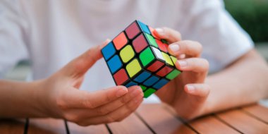 Rubiks küpünü tutan ve masada oynayan sevimli çocuk portresi. Rubiks küpü çocukların elinde. Pankart.