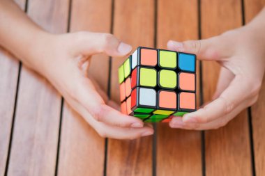 Eller Rubiks küpünü tutuyor ve masada oynuyor. Rubiks küpü çocukların elinde. Pankart.