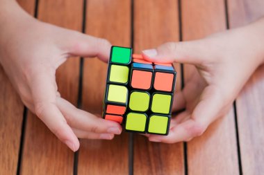 Eller Rubiks küpünü tutuyor ve masada oynuyor. Rubiks küpü çocukların elinde. Pankart.