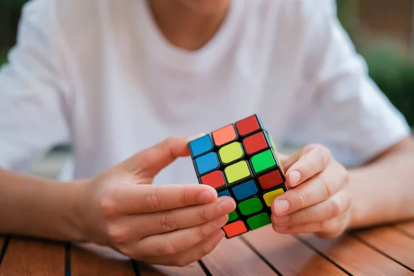 Портрет милого мальчика, держащего кубик Рубика и играющего с ним за столом. Куб Рубика в детские руки. Баннер . — стоковое фото