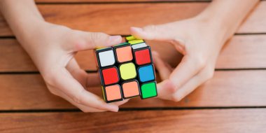 Rubiks küpünü tutan ve masada oynayan sevimli çocuk portresi. Rubiks küpü çocukların elinde. Pankart.