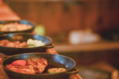 Lokantadaki ahşap bir tahtanın üzerinde yapılan mangalda kızartılmış biftek ve kızarmış sebzeler..