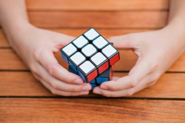 Rubiks küpünü tutan ve masada oynayan sevimli çocuk portresi. Rubiks küpü çocukların elinde. Pankart.