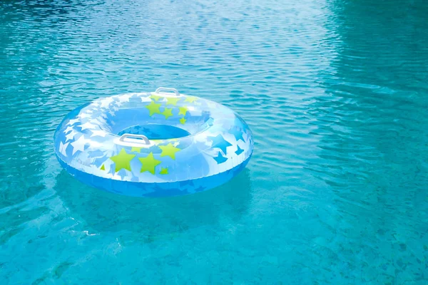 Blue and yellow pool float, ring floating in a refreshing blue swimming pool. Empty swimmig pool. Copy space banner.