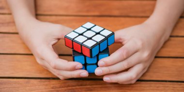 Rubiks küpünü tutan ve masada oynayan sevimli çocuk portresi. Rubiks küpü çocukların elinde. Pankart.