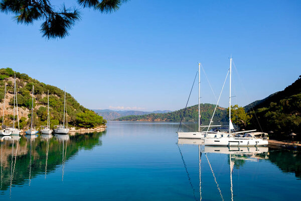 Luxury yachts docked in sea port at sunset. A stunning view of mega yachts in the port. Mountains background.