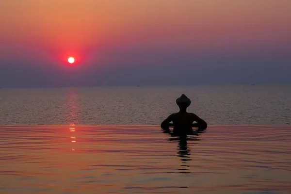 Felice ragazzo adolescente in vacanza in piscina acqua blu. Vista dal retro. Copia banner spaziale. Tramonto . — Foto Stock