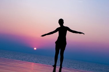 Havuzda gün batımının tadını çıkaran genç bir çocuk. Batan güneşin üzerinde insan silueti. Akşamları yüzme havuzu.