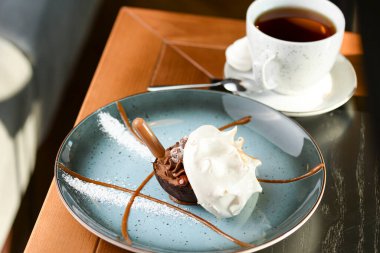 Lokantada bir fincan çayla mavi tabakta servis edilen lezzetli tatlı. Yemek fotoğrafçılığı konsepti.