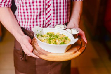 Garson, beyaz tabakta soslu makarna servis ediyor. Lezzetli ve sağlıklı bir yemek konsepti. Restoran servisi. İşte üniformalı garson..