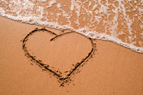 Heart drawn on sand, seacoast. Golden sand beach close up, summer holidays border frame concept. Tourist travel banner design template, copy space. Love symbol, heart shape.