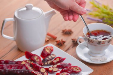 Lezzetli oryantal tatlılar. Kafkasya usulü leziz kilise kilisesi - Gürcü fındık ikramı. Bir bardak çay ve çaydanlıkla servis edilir. Tatlılarla çay zamanı. Geleneksel Gürcü mutfağı. El çay karıştırır..