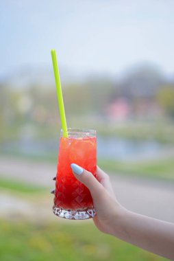 Bulanık arka planda el sıkışma kokteyli. Kırmızı sağlıklı smoothie içmek. Mevsimlik kokteyl. Yaz alkollü kokteyl buzlu içecek..