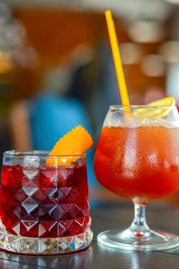 Koyu renkli ahşap bir masada servis edilen bulanık arka planı olan renkli, ferahlatıcı iki kokteyl. Yaz mevsimi alkollü içecekler bir barda ya da restoranda.