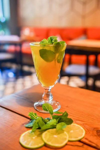 ミントと冷たい柑橘類の飲み物をリフレッシュします 冷たい夏の飲み物はガラスで提供しています 木製のテーブルの上にアルコールカクテル ぼやけたレストランの背景 コンセプトを食べる — ストック写真