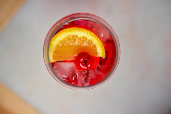 柑橘类水果鸡尾酒 色泽鲜红 背景为黑色 放在木制桌子上的酒杯里用木桌上的冰块和樱桃重新装饰夏季的酒精饮料 — 图库照片