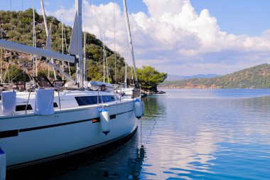 Şatafatlı yatlar gün batımında limana yanaştı. Limandaki büyük yatların göz kamaştırıcı manzarası. Modern motorlu teknelerin ve mavi suların deniz parkı. Rahatlama ve şık bir tatil. Dağların arkaplanı.