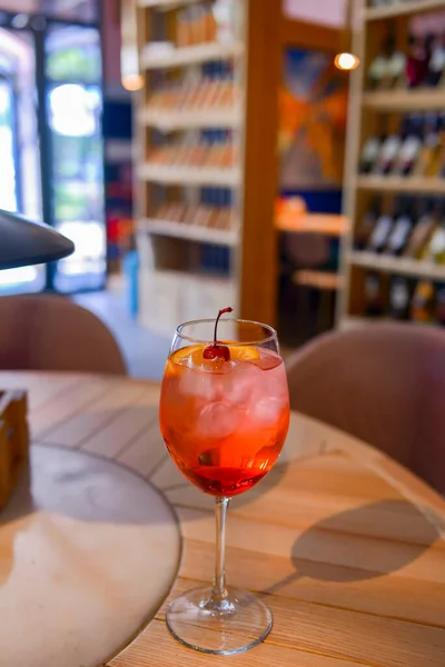 一杯带有红色柑橘鸡尾酒的杯子 酒精夏季饮料在酒杯中 在餐馆内的木制桌子上用冰块重新装饰饮料 外出就餐的概念 模糊的背景 — 图库照片