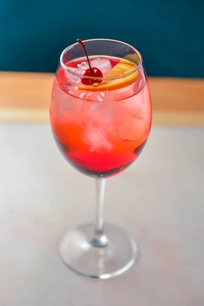柑橘类水果鸡尾酒 色泽鲜红 背景为黑色 放在木制桌子上的酒杯里用木桌上的冰块和樱桃重新装饰夏季的酒精饮料 — 图库照片