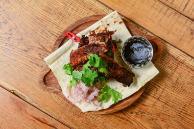 Gürcü yemeği. Köy ahşabının üzerinde ahşap bir tahtada servis edilen taze yeşillikli ızgara et bifteği. Geleneksel mutfak konsepti, lezzetli yemek..