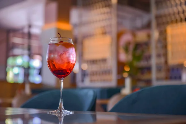 赤い柑橘系のカクテルとガラス ワイングラスでアルコール夏の飲料 レストラン内の木のテーブルの上に氷でリフレッシュドリンク コンセプトを食べる ぼやけた背景 — ストック写真