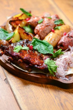 Gürcü yemeği. Et, sosis ve ahşap bir masada servis edilen taze yeşillikli fırında patates. Geleneksel mutfak konsepti, lezzetli yemek..