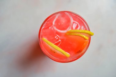 Siyah arka planda kırmızı renkli, turunçgil meyveli kokteyl. Tahta bir masada şarap kadehinde servis edilmiş. Tahta bir masada buzlu ve kirazlı alkollü yaz içeceği.