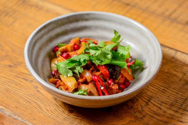 Gürcü sebze ve soğanlı et salatası, fesleğen, domates, maydanoz ve biber. Geleneksel yemek, Gürcü mutfağı konsepti. Kaba ahşap bir masada servis edilen salata..