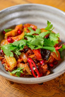 Gürcü sebze ve soğanlı et salatası, fesleğen, domates, maydanoz ve biber. Geleneksel yemek, Gürcü mutfağı konsepti. Kaba ahşap bir masada servis edilen salata..