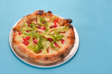 Pastel mavi arka planda somon ve avokado ile izole edilmiş pizza. Geleneksel İtalyan yemeği konsepti, deniz ürünleri pizzası. Sağlıklı ve lezzetli yemek konsepti.