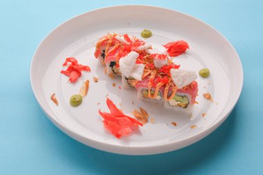 Philadelphia 'yı taze somon ve krem peynirden yap. Turşulu zencefil ve wasabi soslu somon suşisi. Geleneksel Japon mutfağı kavramı. Mavi pastel arkaplanda izole.