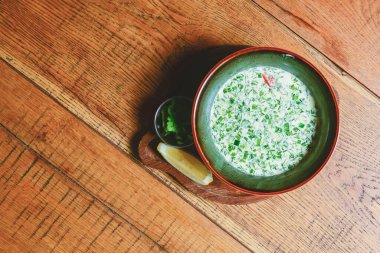 Popüler ilkbahar ve yaz soğuk çorba okroshka. Okroshka kasede, limon ve otlar kırsal ahşap masada. Geleneksel mutfak konsepti, Gürcü mutfağı, Rus mutfağı. Boşluk afişini kopyala.