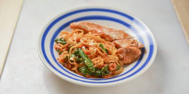 Et soslu fesleğenli spagetti. Geleneksel İtalyan makarnası ızgara et ile ahşap masanın üzerinde beyaz bir tabakta servis ediliyor. İtalyan mutfağı kavramı.