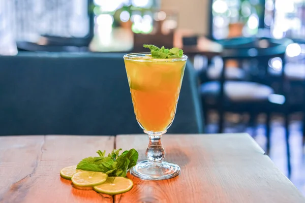 さわやかな夏の飲み物 レモンとライムと冷たいアルコール飲料 ぼやけたレストランやバットの背景の上に素朴な木製のテーブルの上にガラスの柑橘類のカクテル コンセプトを食べる — ストック写真
