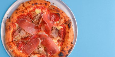 Peynirli ve mantarlı İtalyan pizzası. Parlak mavi pastel fırının üzerinde metal bir tepside. Uzay afişini kopyala. İtalyan mutfağı konsepti, geleneksel yemek.