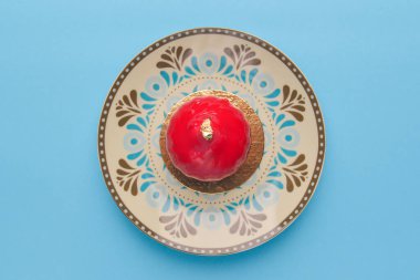 Kutlama ya da sevgililer günü için tatlı kaplı gurme kırmızı çikolata. Parlak pastel mavi arka planda eşsiz bir tabakta servis ediliyor. Boşluk afişini kopyala.