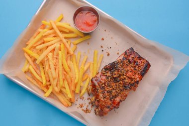 Barbekü soslu pirzola ve soslu patates kızartması. Metal bir tepside servis edilen baharatlı ve soslu ızgara pirzola..